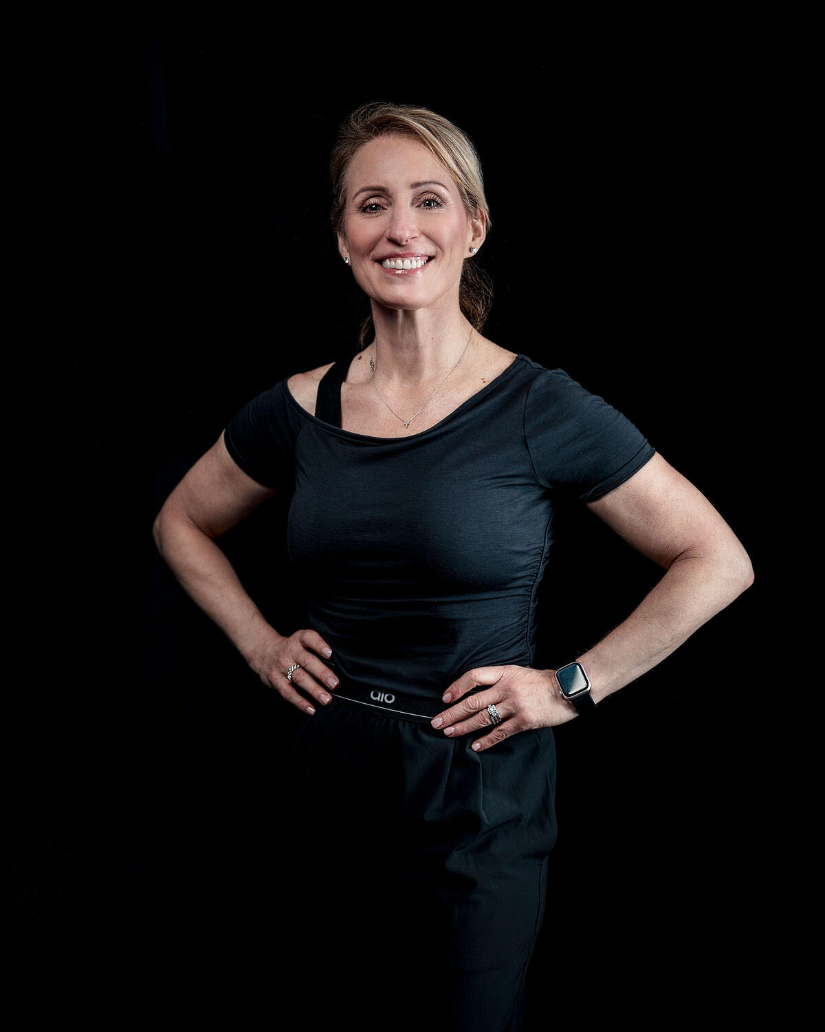 Lena Peron in black, smiling, hands on her hips